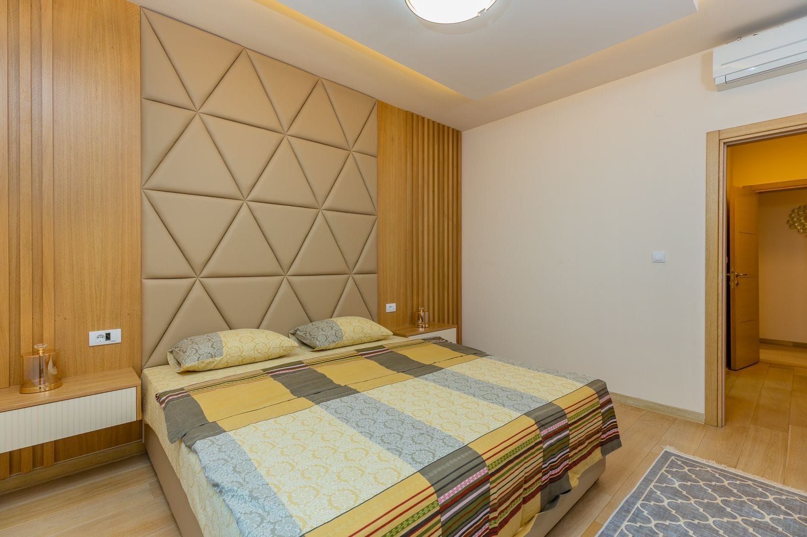 Modern bedroom with a double bed and upholstered headboard in a penthouse, Pržno, Montenegro.