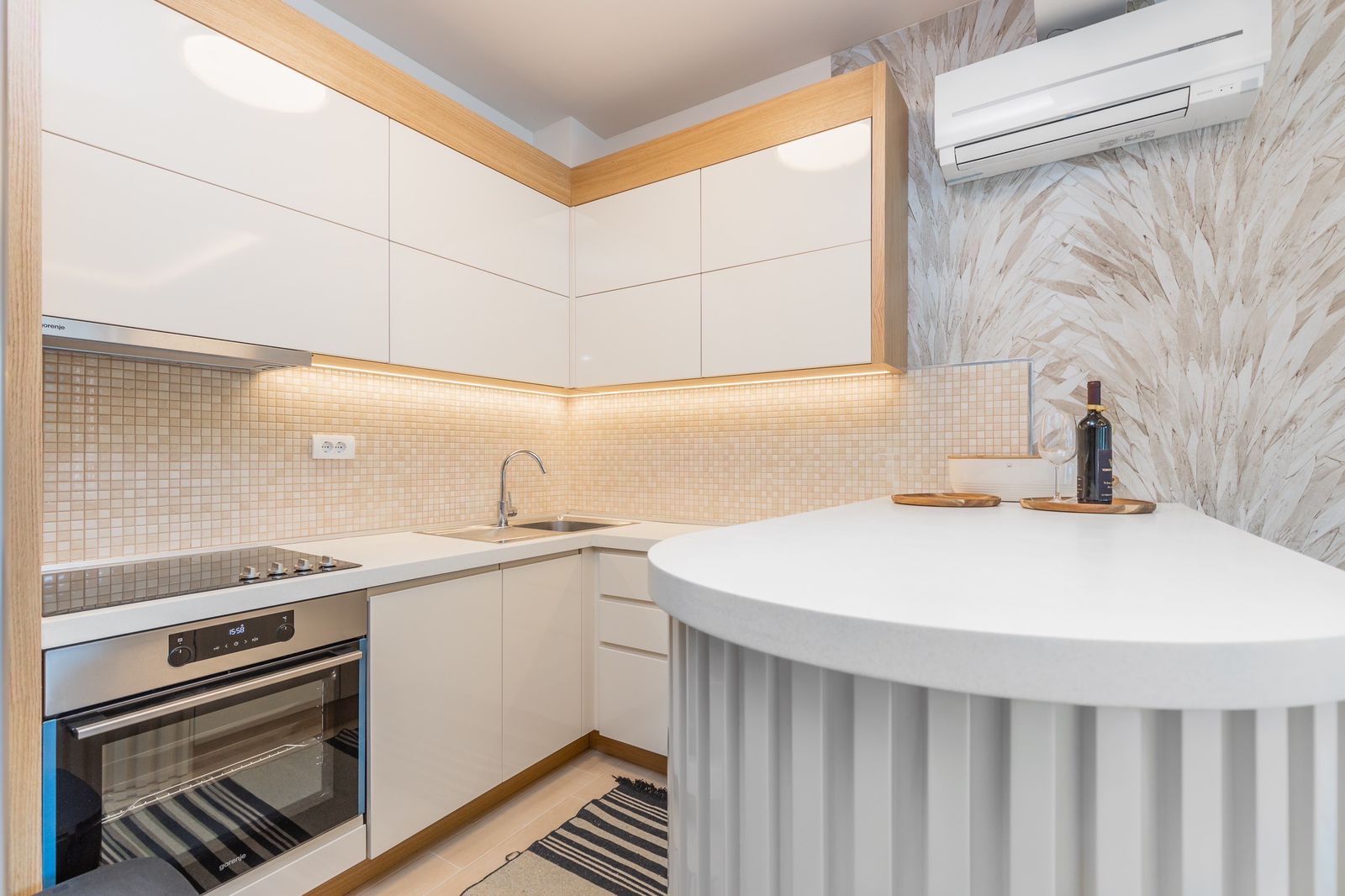 Modern kitchen in a penthouse in Pržno, Montenegro: white cabinetry, a bar counter, built-in appliances, and accent lighting.