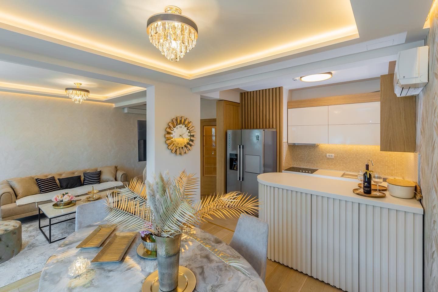 Modern living room with kitchen in a penthouse, Pržno, Montenegro: marble table, beige sofa, and designer lighting.