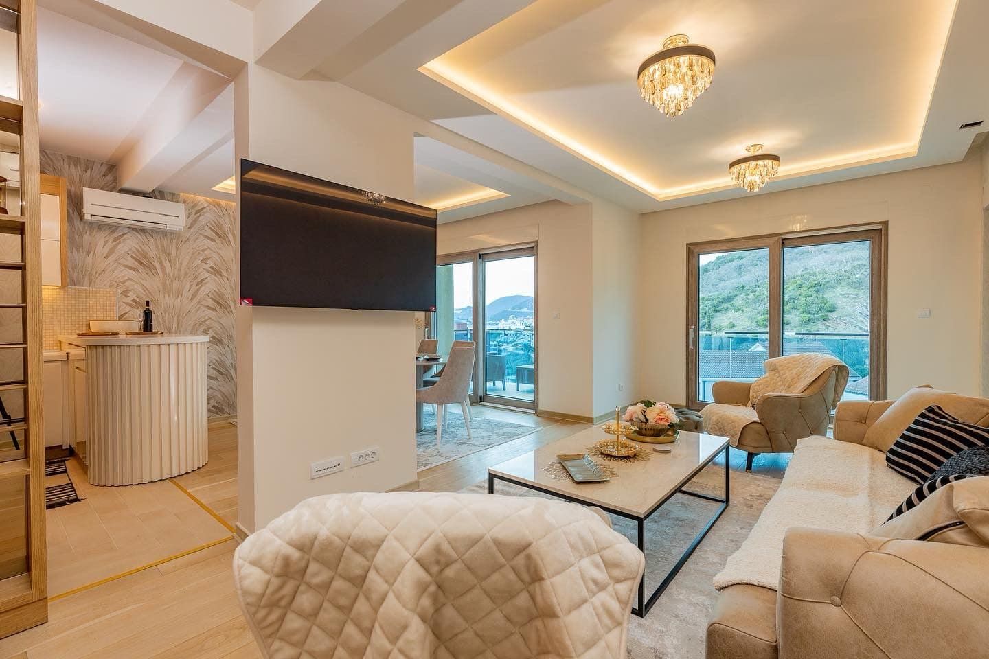 Modern living room in a penthouse in Pržno, Montenegro: light furniture, panoramic windows, and views of the mountains and sea.