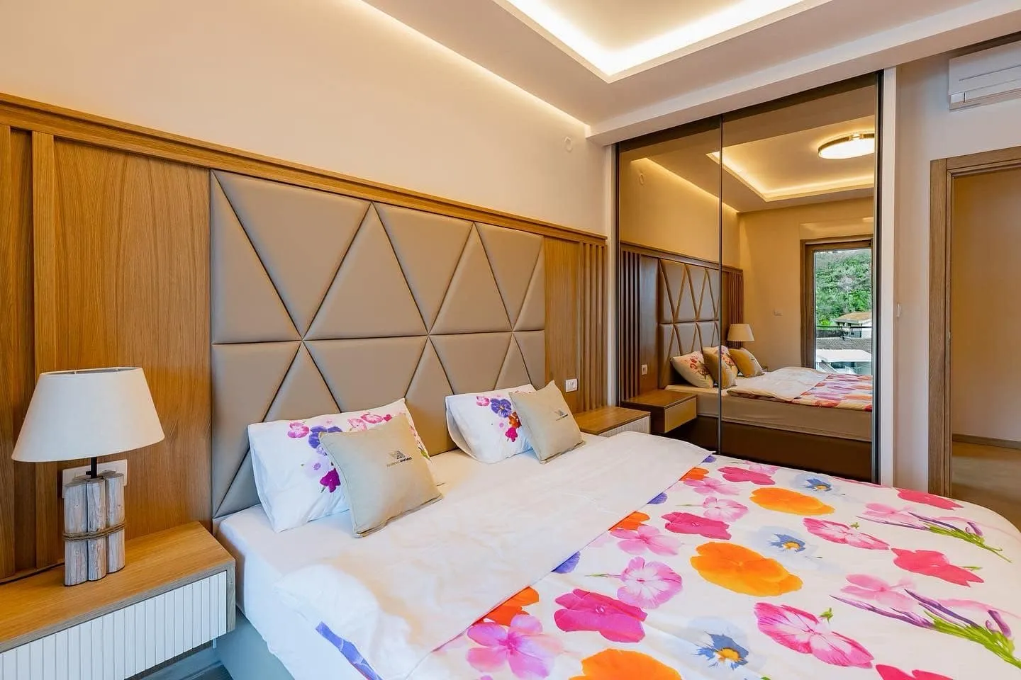 Nowoczesna sypialnia w penthousie w Pržnie, Czarnogóra: łóżko podwójne, miękkie zagłowie i lustrzana szafa przesuwna.