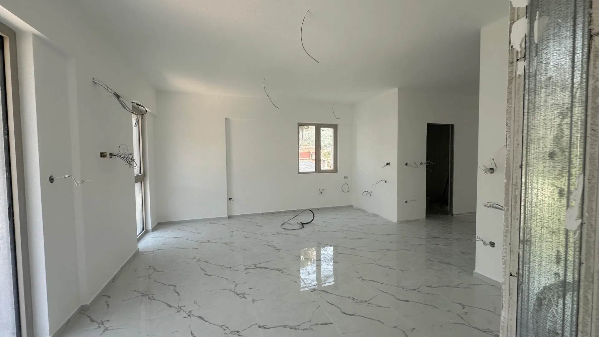 Wohnzimmer in einem Neubau in Budva, Montenegro: helle Ausstattung, Marmorboden und Elektrovorbereitung, Blick auf die Stadt.