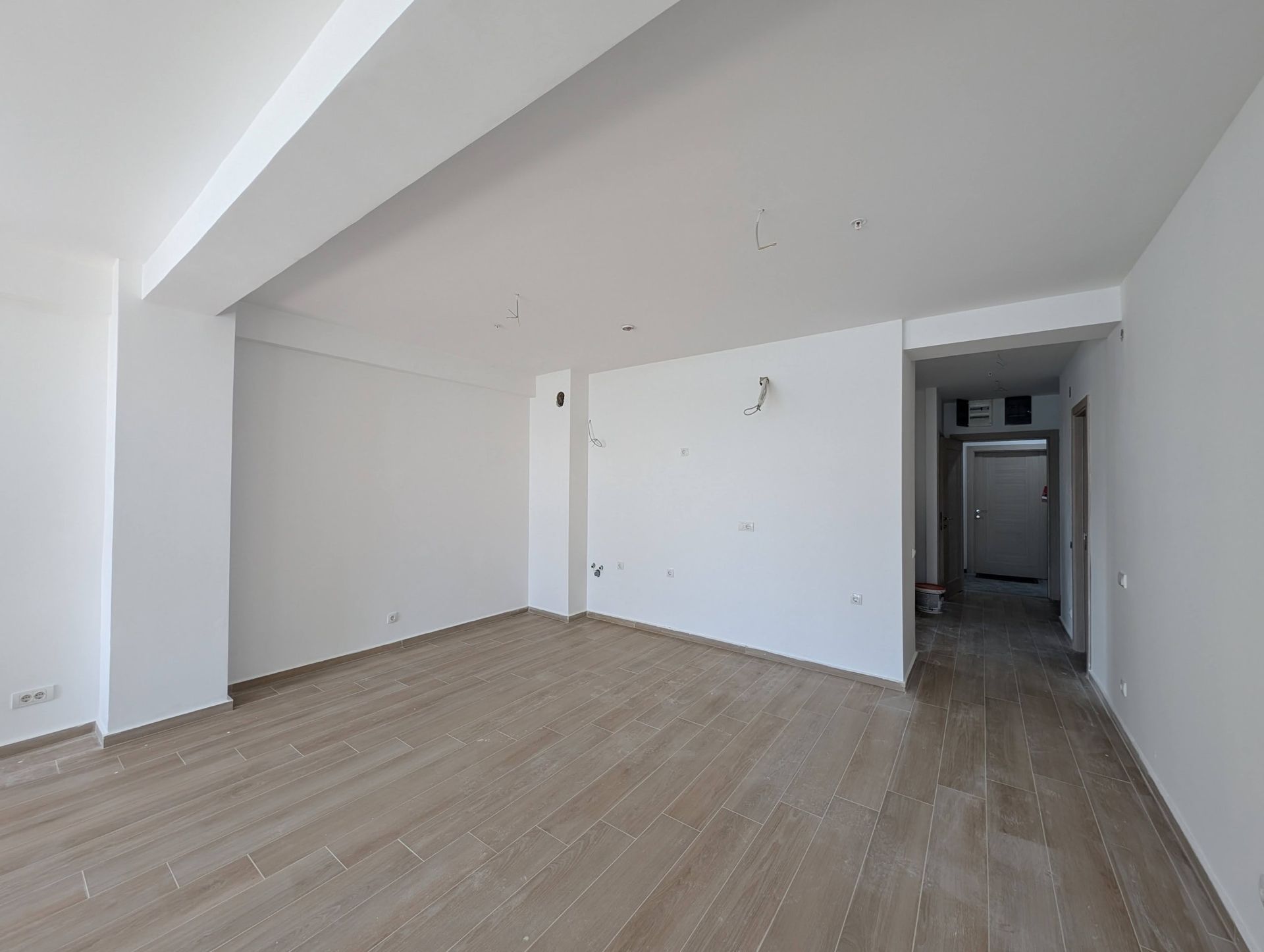 Salon blanc dans un nouvel immeuble à Rafailovići, Monténégro, avec finition clé en main, murs blancs et plancher en bois.