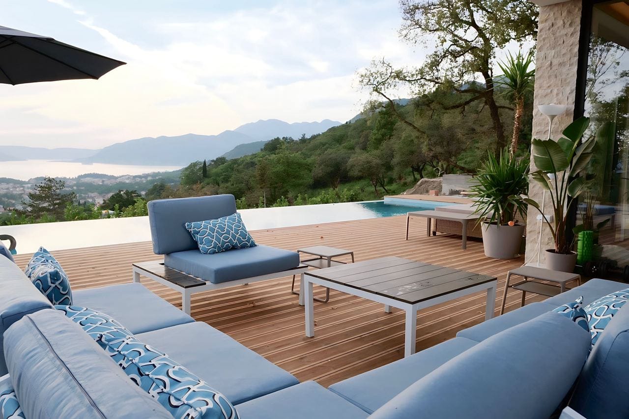 Terrasse mit Pool und Blick auf die Berge und die Bucht in der Wohnanlage Kavac, Montenegro: moderne Möbel und Holzdeck.