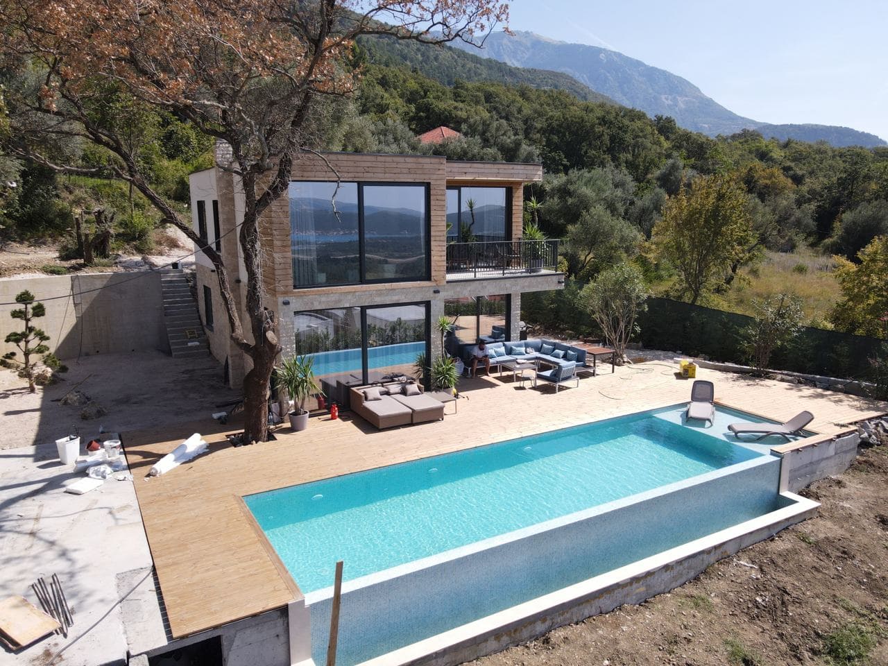 Moderne Villa mit Panoramafenstern, Pool und Terrasse in Kavac, Montenegro. Blick auf die Berge und die Wohnanlage.