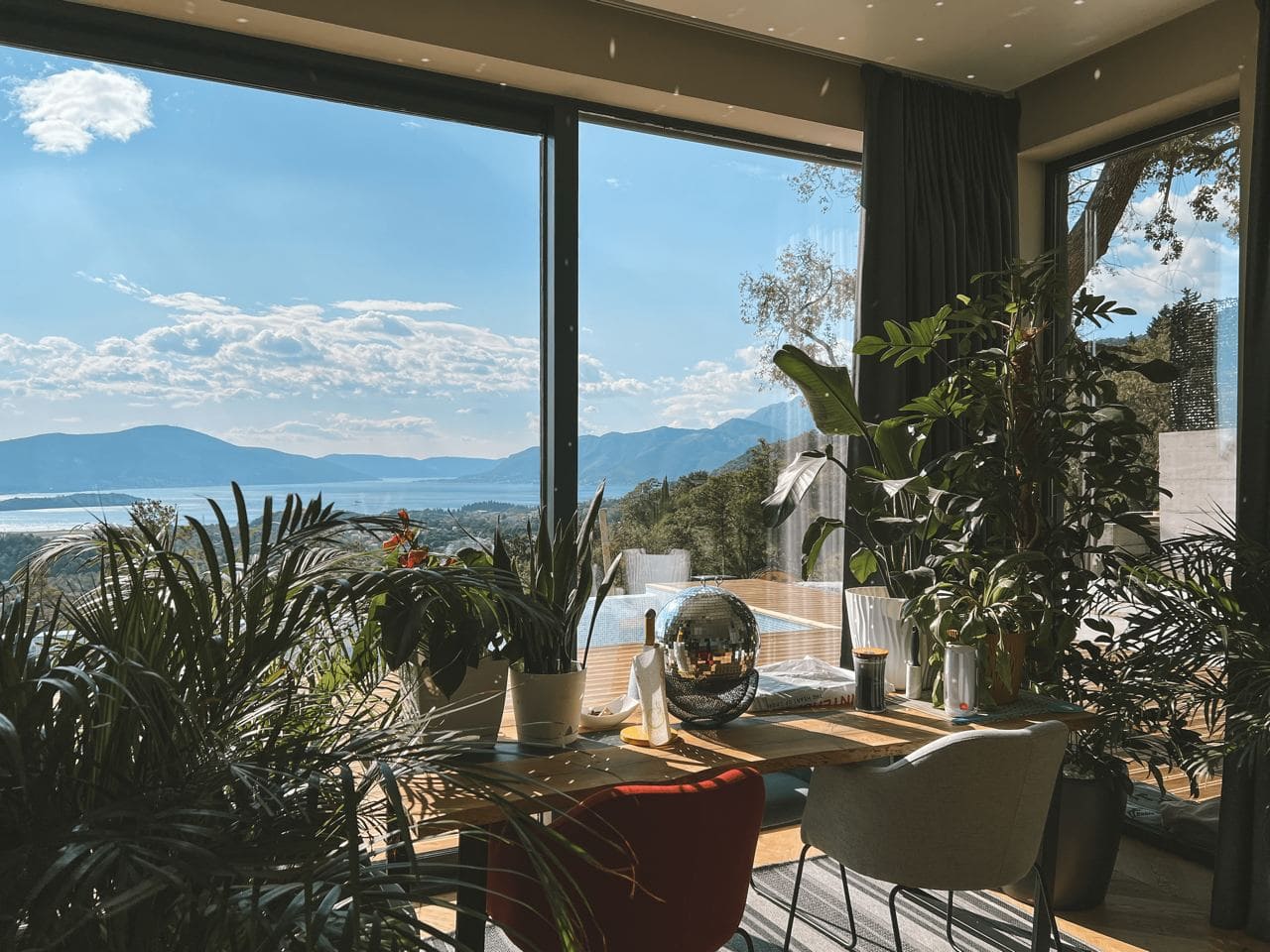 Wohnzimmer mit Panoramafenstern und Meerblick in der Wohnanlage Kavac, Montenegro: stilvolles Interieur mit Pflanzen und Terrasse.