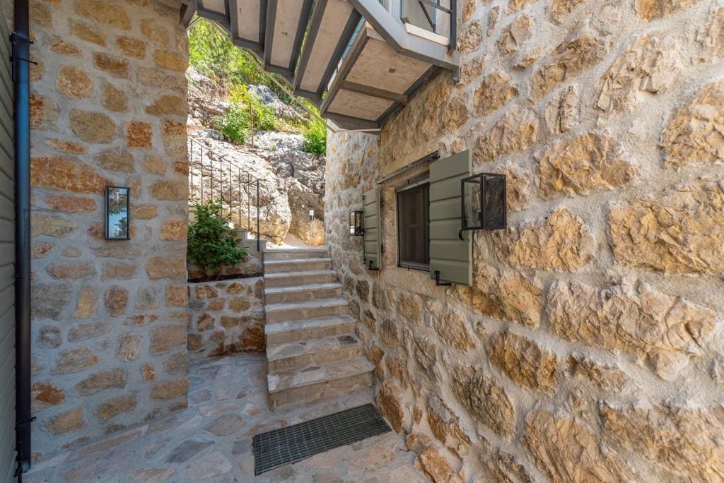Escalier en pierre et façade de la villa à Herceg Novi, Monténégro : finition traditionnelle en pierre et cour intérieure accueillante.