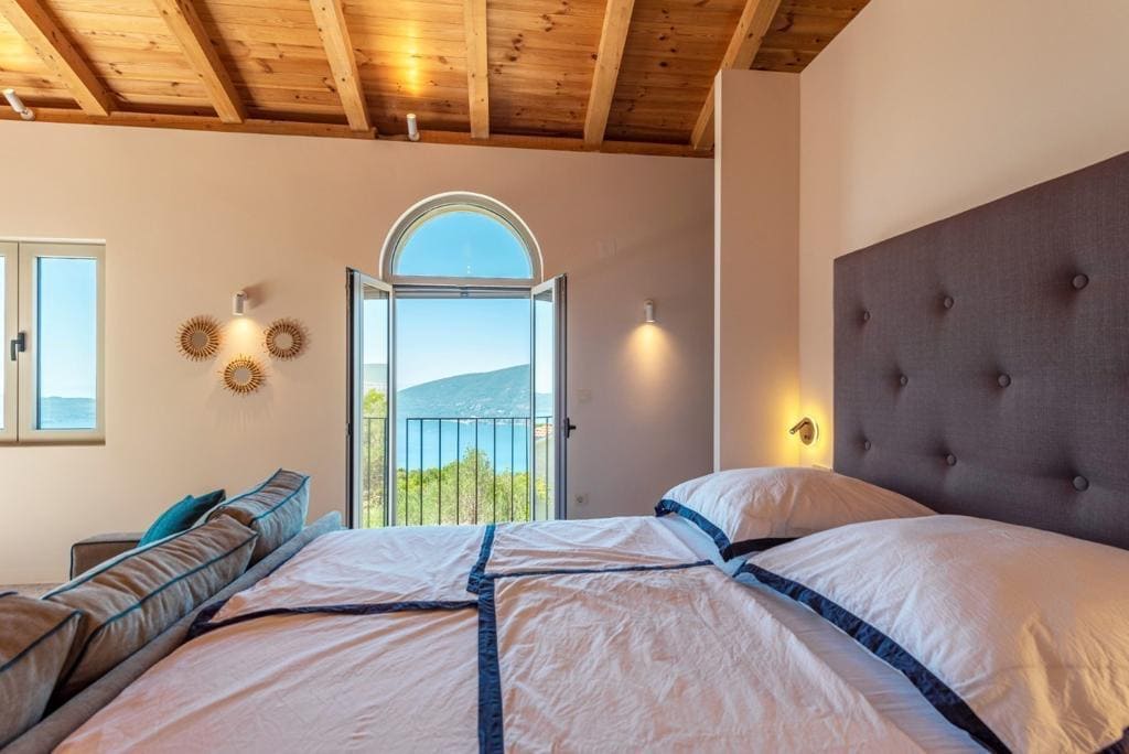 Chambre à coucher dans une villa à Herceg Novi, Monténégro : lit double, plafond en bois et balcon avec vue sur la mer.