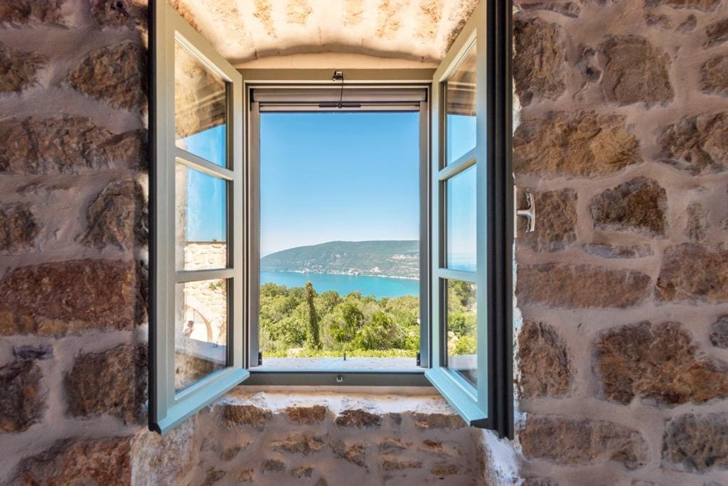 Vue sur la mer et les montagnes depuis la fenêtre d’une villa en pierre à Herceg Novi, Monténégro : intérieur avec murs en maçonnerie authentique.