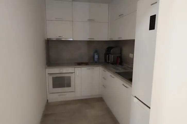 Moderne weiße Küche in einer Wohnung in Budva, Montenegro: Einbaugeräte, Hochglanzfronten und helle Ausstattung.