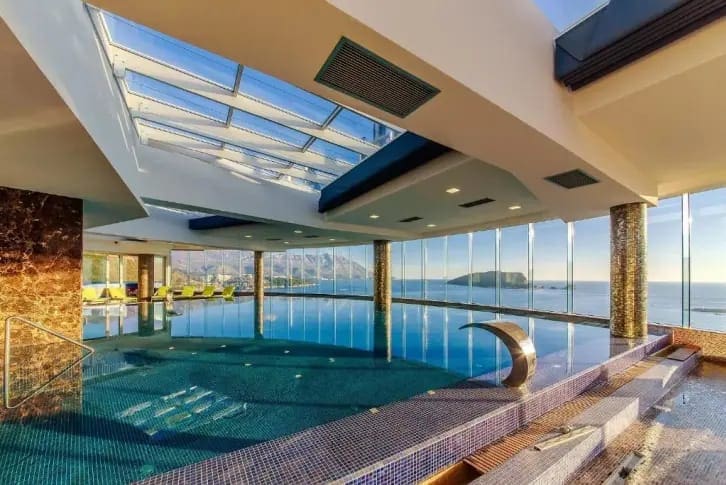 Überdachter Pool mit Panoramablick auf das Meer und die Insel in einer exklusiven Wohnanlage, Budva, Montenegro.