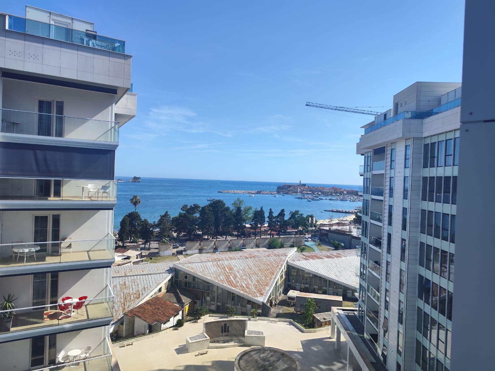 Blick vom Balkon einer modernen Wohnung in Budva, Montenegro: Panorama auf die Adria, den Strand und die Stadtbebauung.
