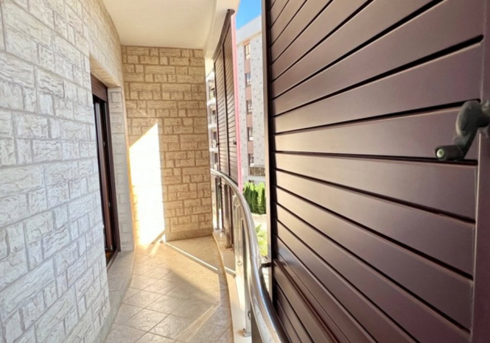 Balkon mit Verkleidung aus dekorativem Stein und Schutzjalousien in einer Wohnung in Bečići, Montenegro.
