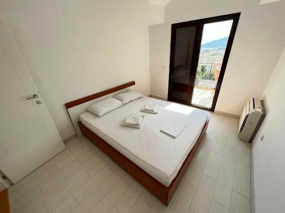 Helles Schlafzimmer mit Doppelbett und Zugang zum Balkon in einer Villa, Budva, Montenegro. Modernes Interieur.