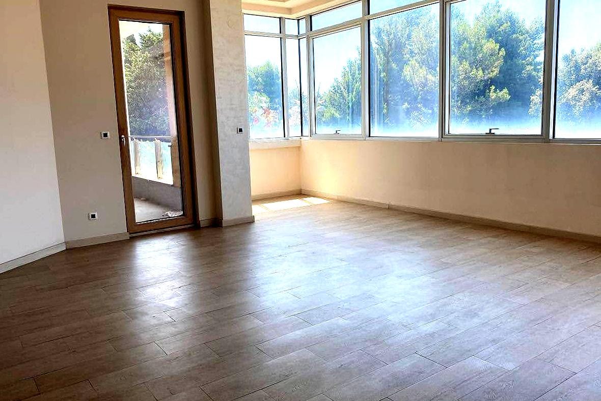 Helles Wohnzimmer mit Panoramafenstern und Zugang zum Balkon in einer Wohnung im Zentrum von Budva, Montenegro.