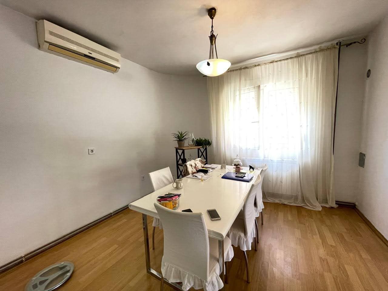 Bar, Karadağ'daki evde yemek alanına sahip aydınlık oturma odası: beyaz masa, sandalyeler ve klima.