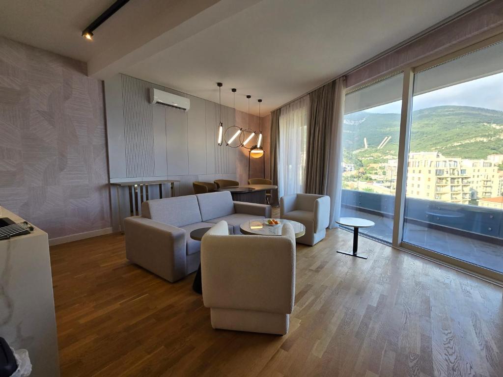 Modernes Wohnzimmer mit Panoramafenstern und Bergblick in einer Wohnung in Bečići, Montenegro: stilvolle Möbel und Parkett.