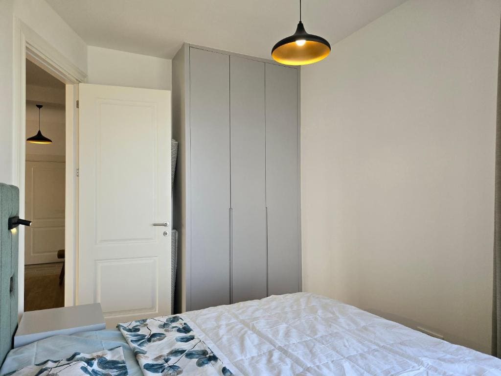 Schlafzimmer in einer Wohnung in Bečići, Montenegro: moderner Einbauschrank, Doppelbett und stilvolle Leuchte.