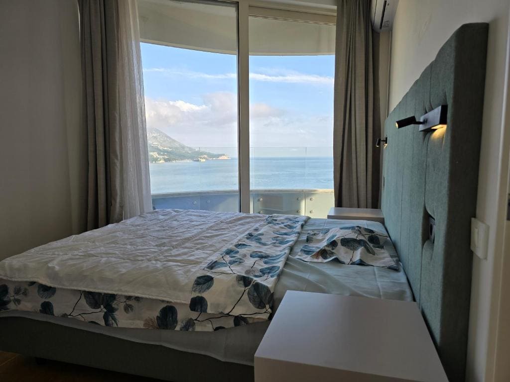 Schlafzimmer mit Doppelbett und Panoramablick auf das Meer in einer Wohnung, Bečići, Montenegro.