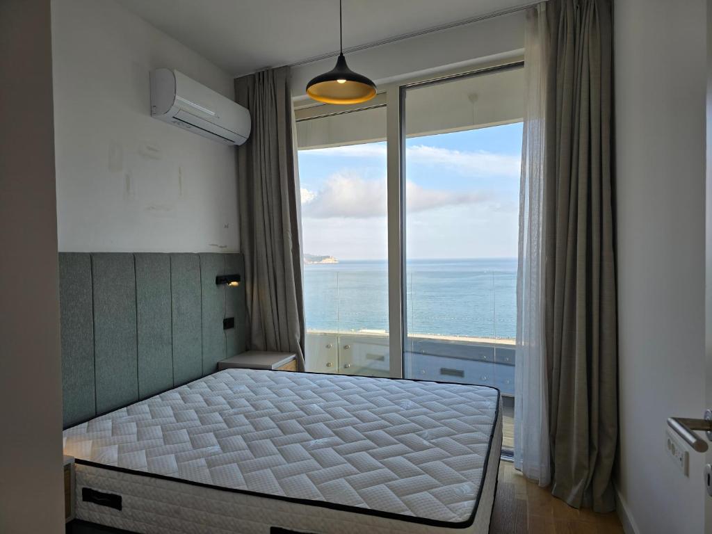 Schlafzimmer in einer Wohnung in Bečići, Montenegro: Doppelbett, Panoramafenster mit Meerblick und Zugang zum Balkon.