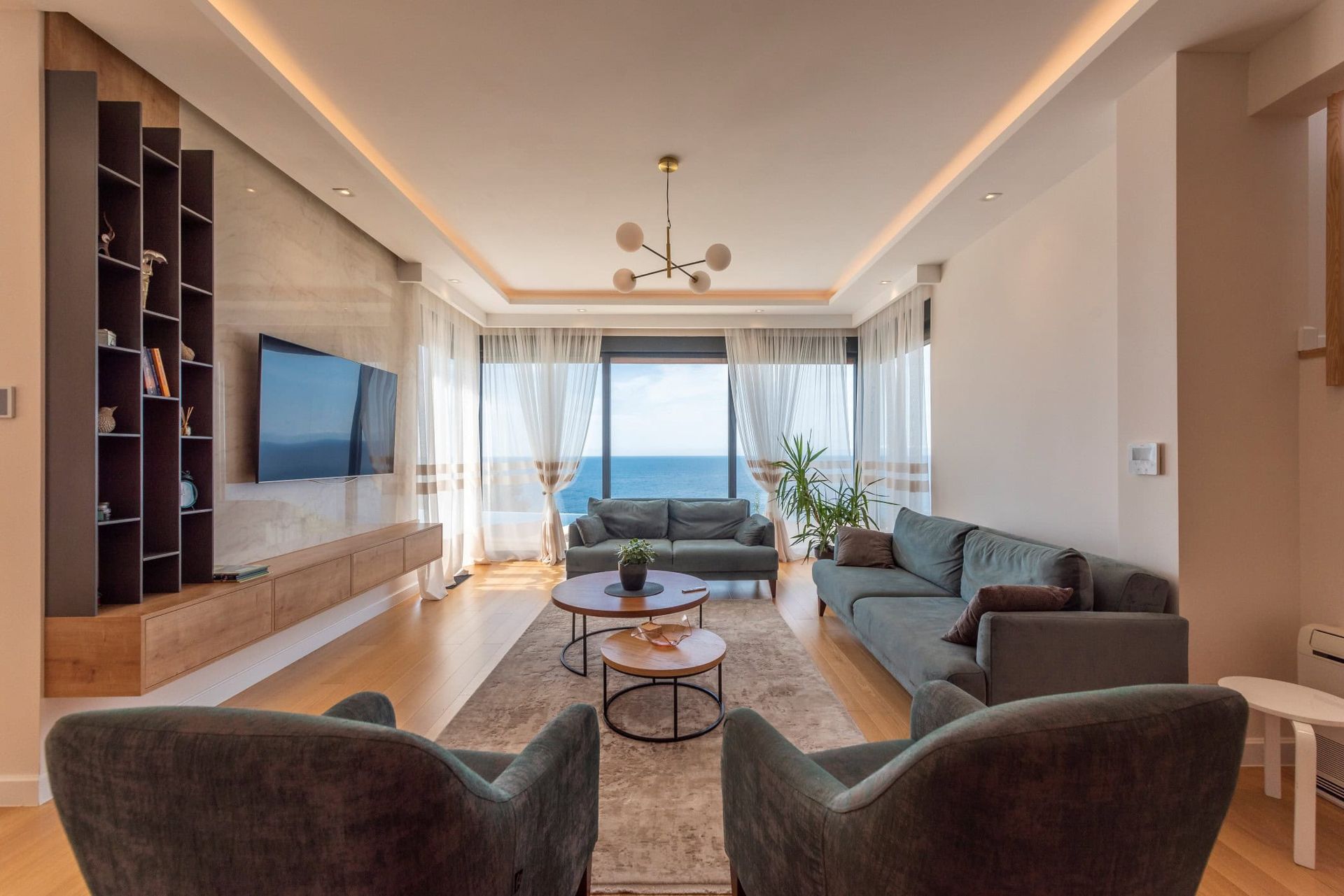 Salon moderne avec vue sur la mer dans une maison, Reževići, Monténégro : mobilier moelleux, baies vitrées panoramiques et design élégant.