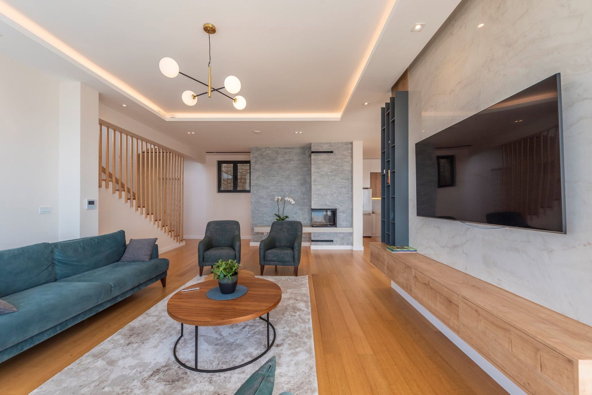 Salon moderne avec cheminée et escalier en bois dans une maison, Reževići, Monténégro. Intérieur avec mobilier rembourré.