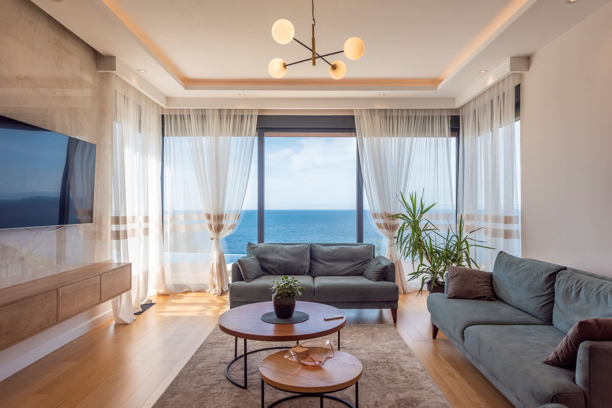 Salon avec vue panoramique sur la mer dans une maison, Reževići, Monténégro : mobilier moderne, intérieur lumineux et terrasse.