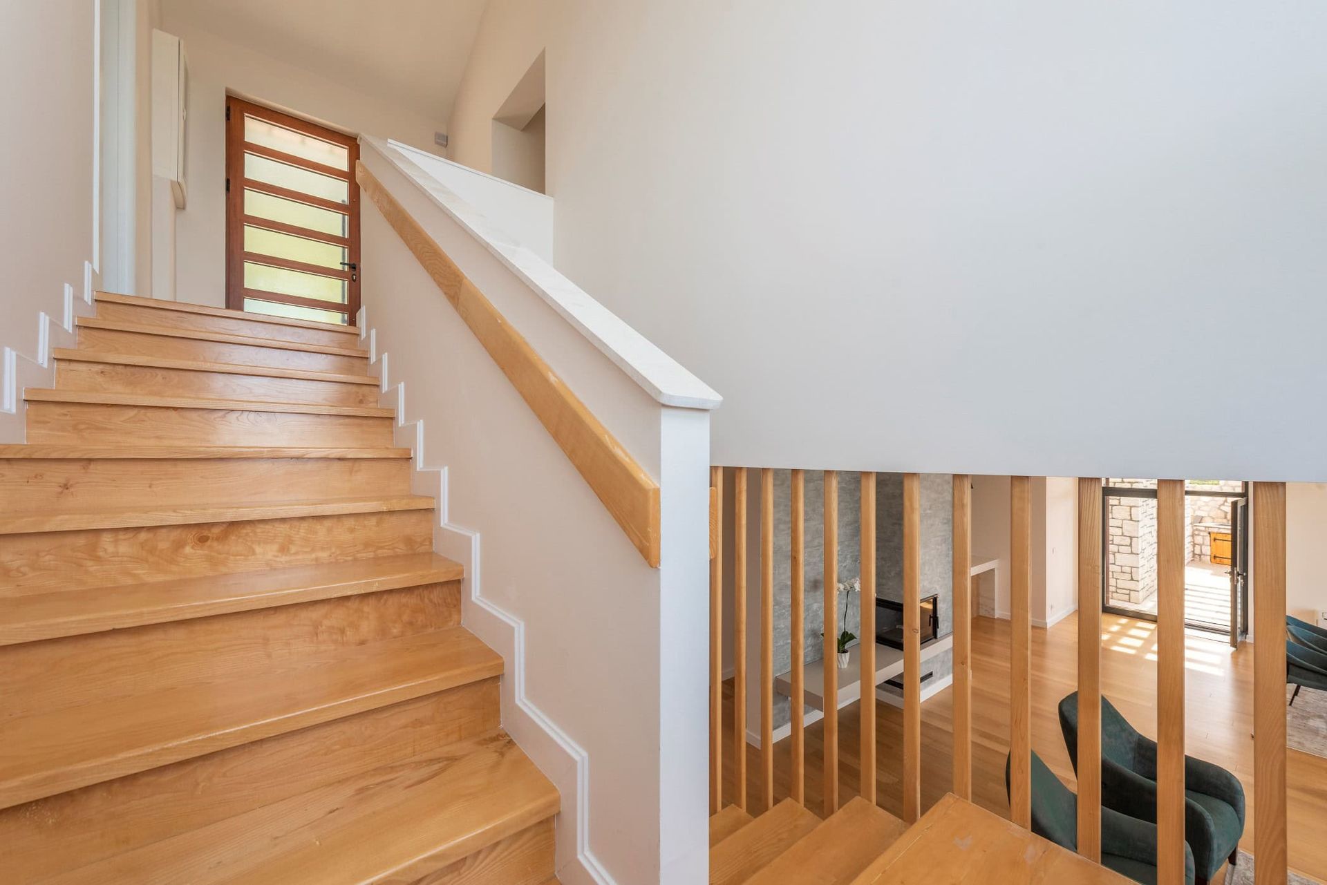 Escalier en bois dans une maison moderne à Reževići, Monténégro : intérieur lumineux, rampe élégante et vue sur le salon.