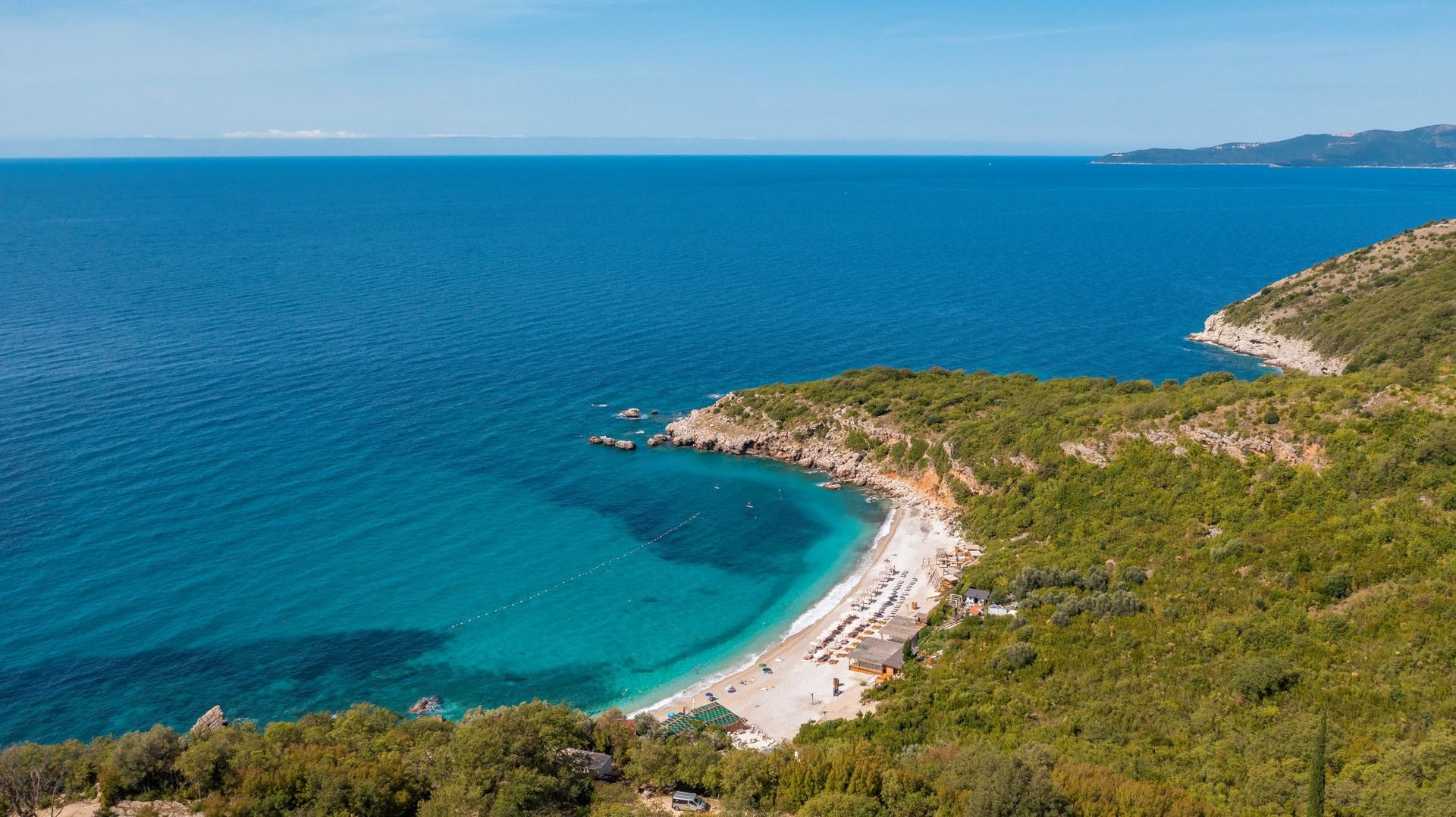 Vue aérienne d’une plage pittoresque et de la mer Adriatique à Reževići, Monténégro, près du bien immobilier.