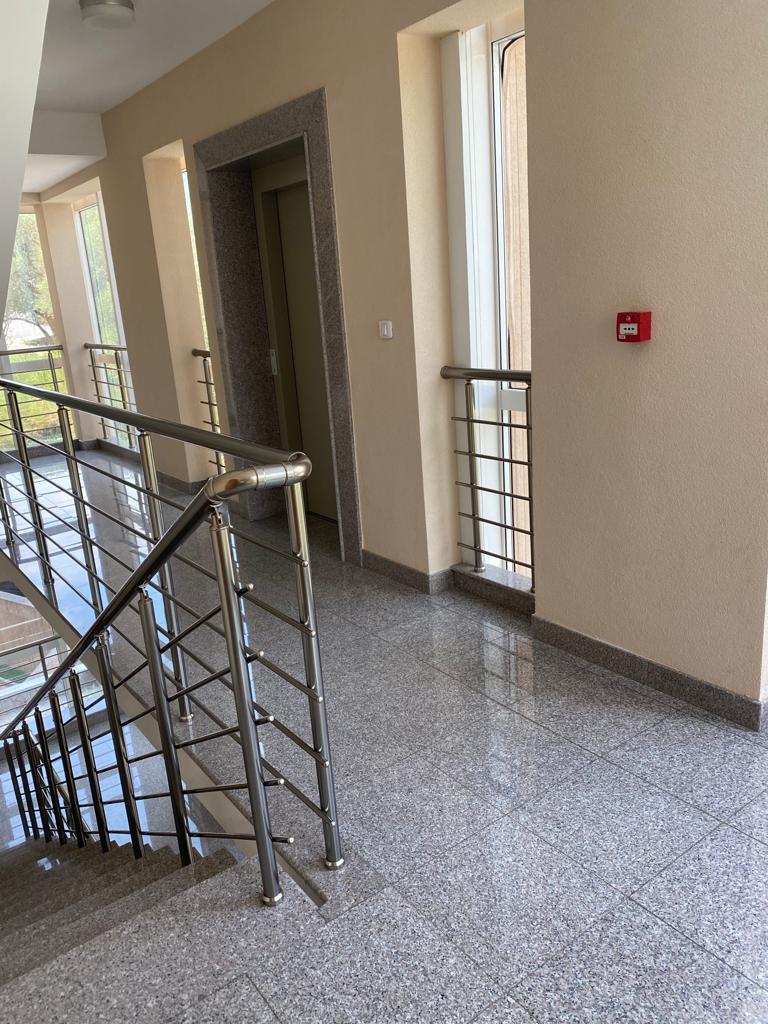 Heller Hauseingang mit Granitboden und Treppe mit Metallgeländer in einer Wohnanlage in Bečići, Montenegro.