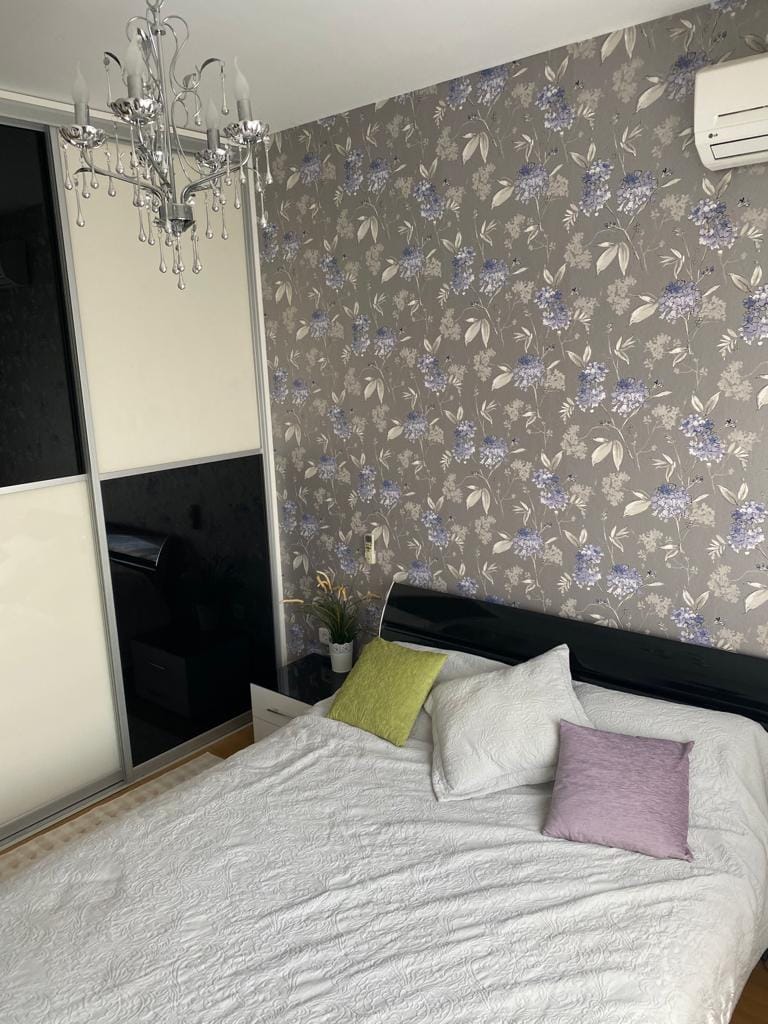Schlafzimmer in einer Wohnung in Bečići, Montenegro: Doppelbett, Einbauschrank, Tapeten mit Blumenmuster und Kronleuchter.