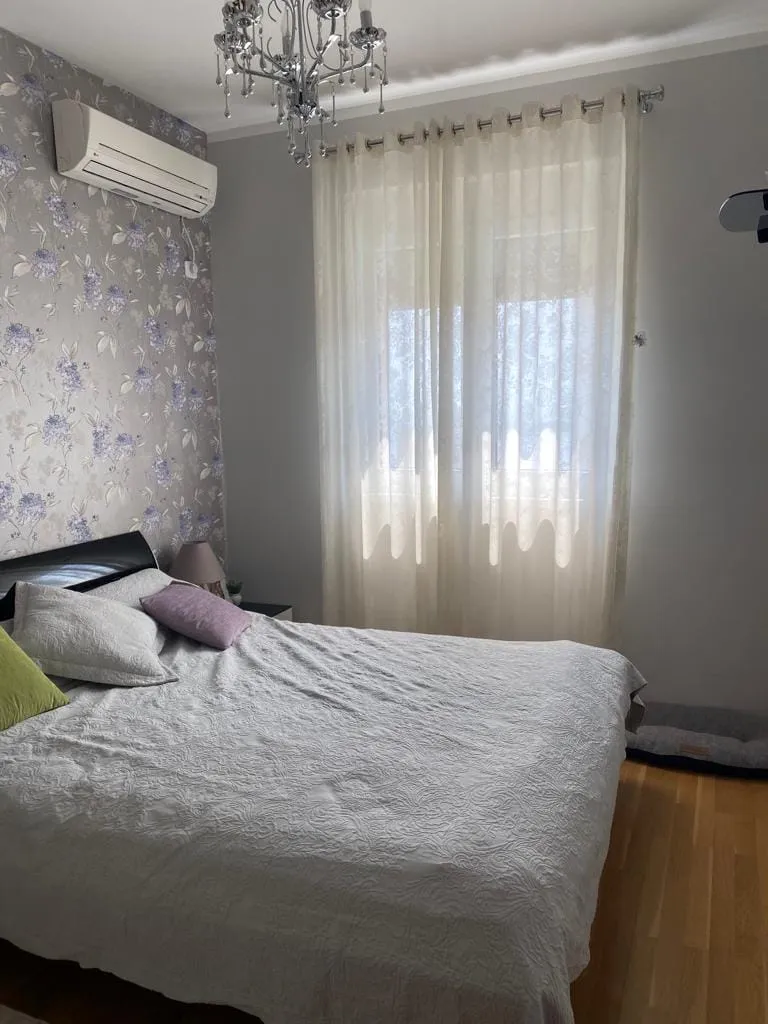 Udobna spavaća soba sa bračnim krevetom u stanu u Bečićima, Crna Gora: tapete sa cvetnim printom, klima-uređaj i parket.