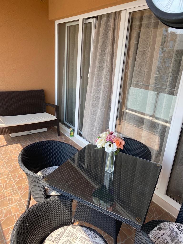 Gemütlicher Balkon mit Rattanmöbeln und Glastisch in einer Wohnung in Bečići, Montenegro.