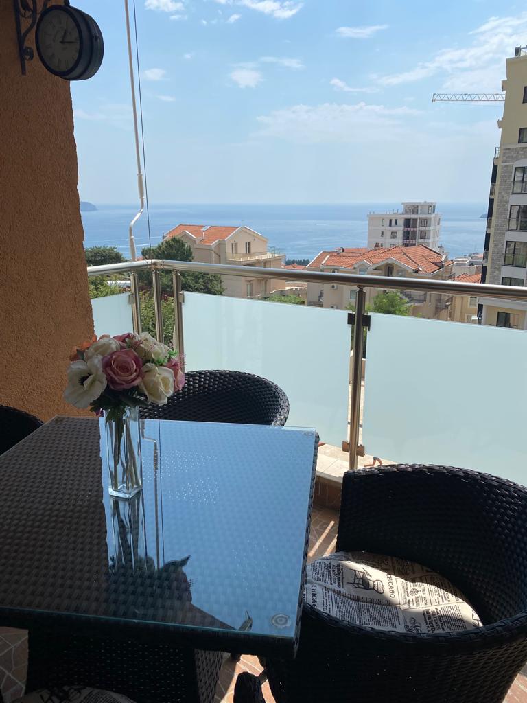 Balkon mit Rattanmöbeln und Meerblick in einer Wohnung in Bečići, Montenegro. Gemütliche Terrasse mit Esstisch.