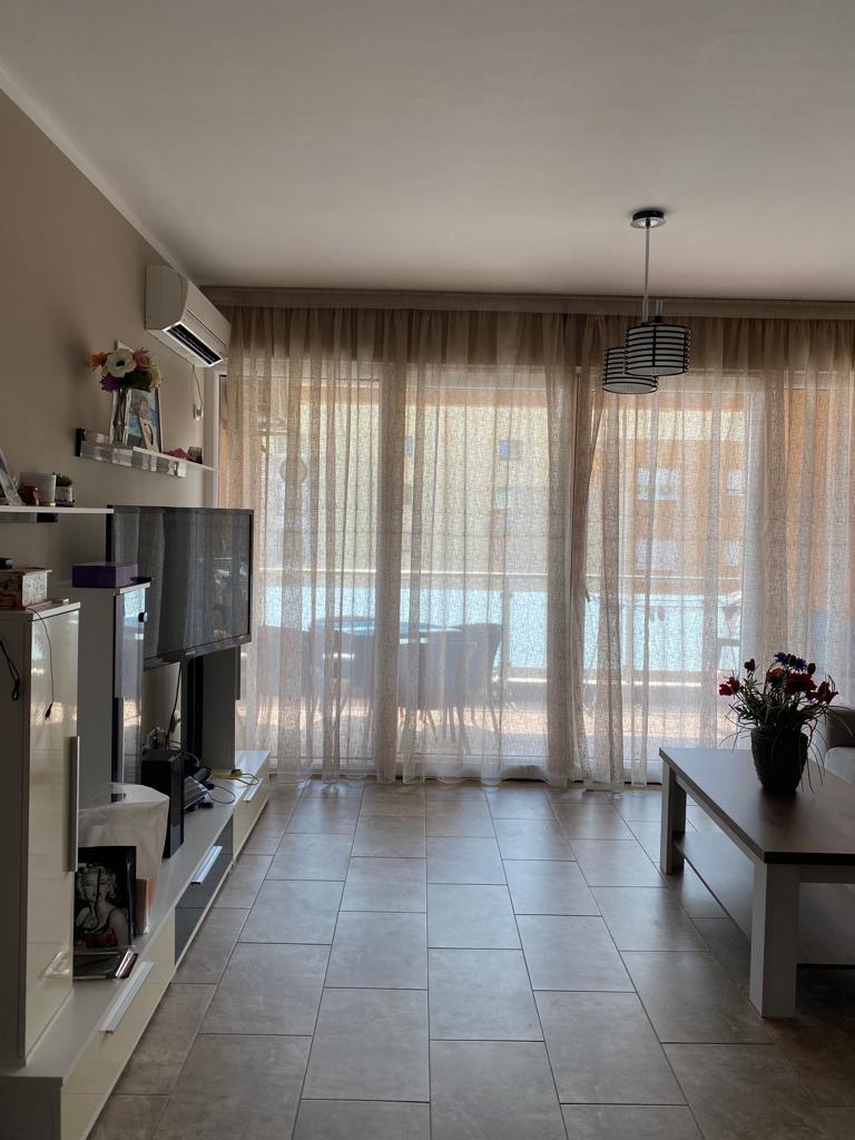 Helles Wohnzimmer in einer Wohnung in Bečići, Montenegro: moderne Möbel, TV-Bereich, Panoramafenster mit Zugang zur Terrasse.