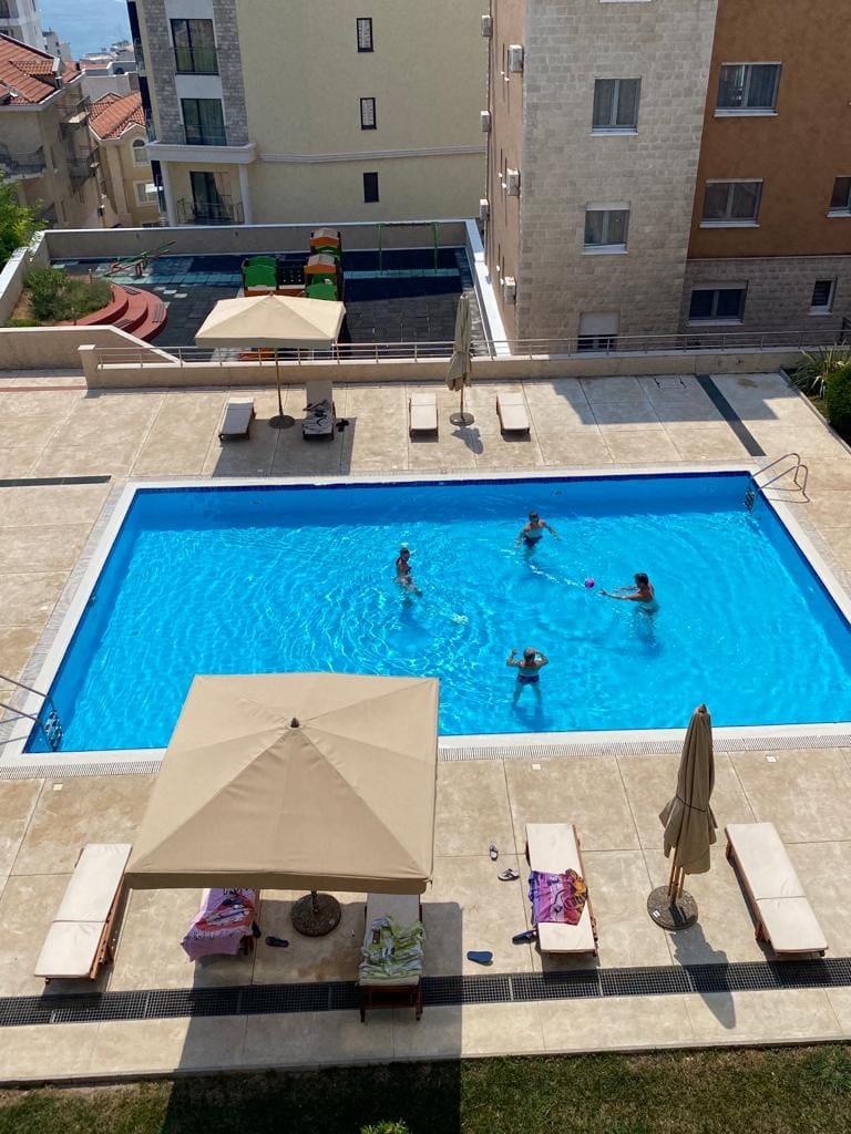 Offener Pool mit Liegestühlen und Sonnenschirmen auf dem Gelände der Wohnanlage in Bečići, Montenegro.