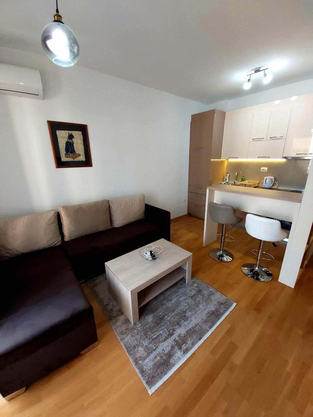 Modernes Wohnzimmer mit Küche in einer Wohnung in Budva, Montenegro: Ecksofa, Bartheke und helle Ausstattung.