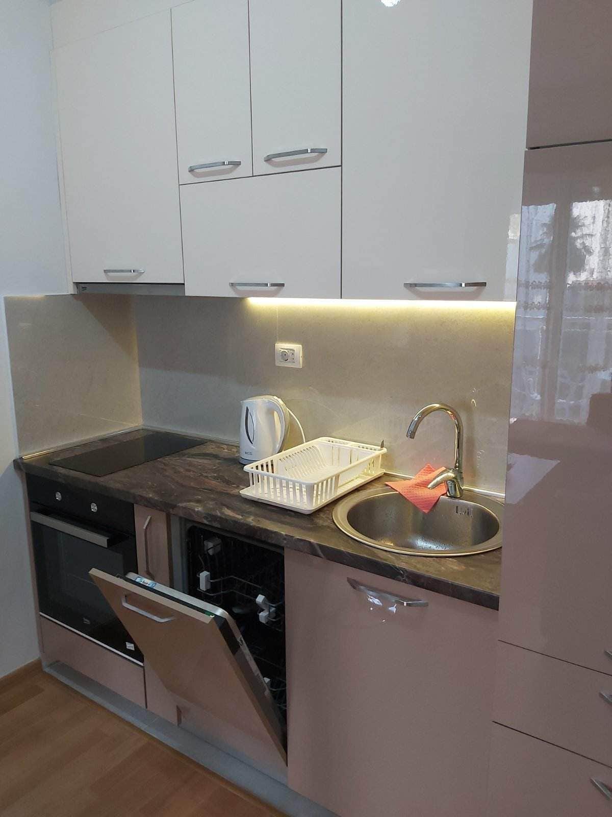 Moderne Küche in einer Wohnung in Budva, Montenegro: glänzende Fronten, eingebautes Kochfeld, Backofen und Geschirrspüler.