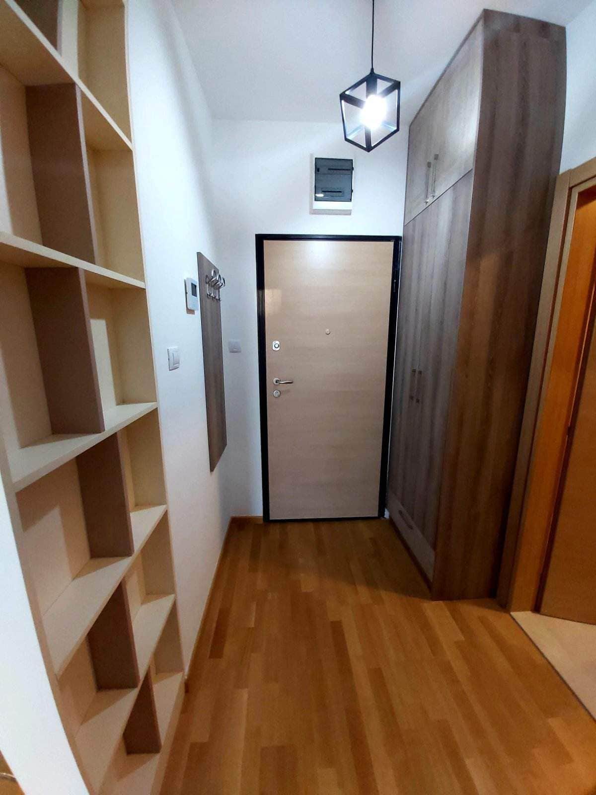 Eingangsbereich in einer Wohnung in Budva, Montenegro: Einbauschrank, offenes Regal, Parkettboden und moderne Beleuchtung.