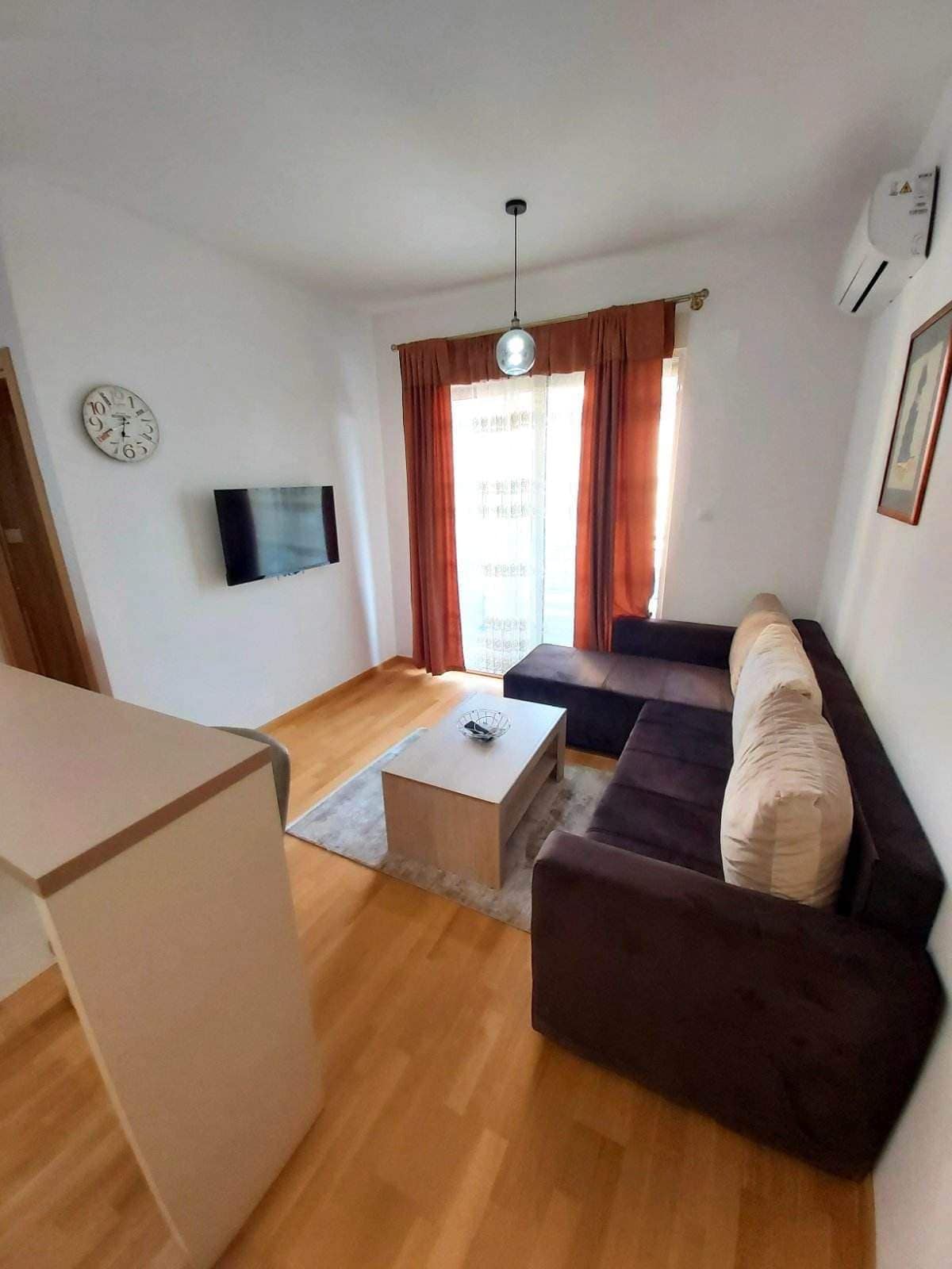 Gemütliches Wohnzimmer mit Ecksofa und Zugang zum Balkon in einer Wohnung in Budva, Montenegro. Modernes Interieur.