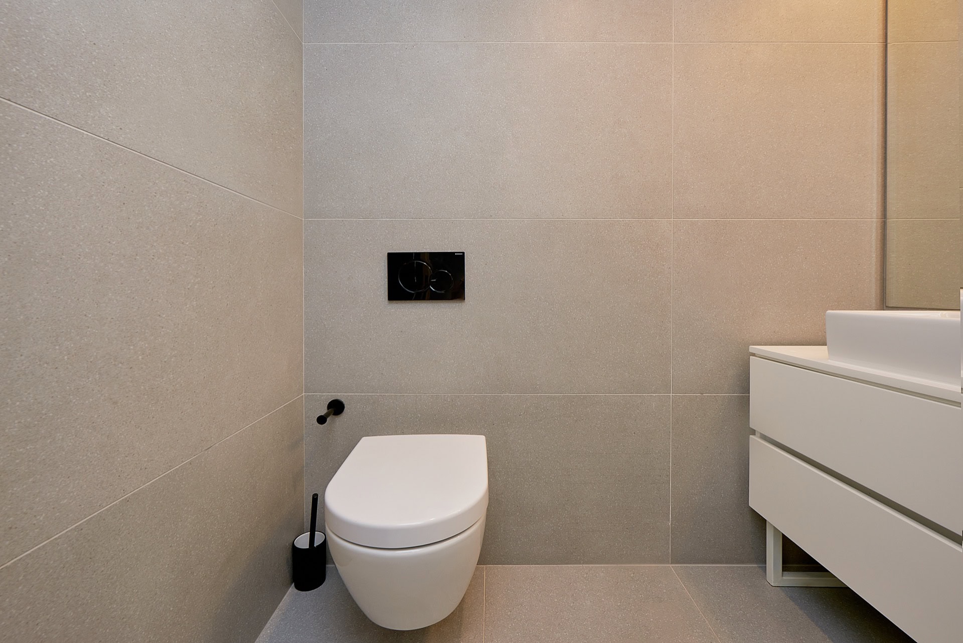 Modernes Badezimmer in einer Wohnung in Budva, Montenegro: Hänge-WC, weißer Waschtischunterschrank und Feinsteinzeug.