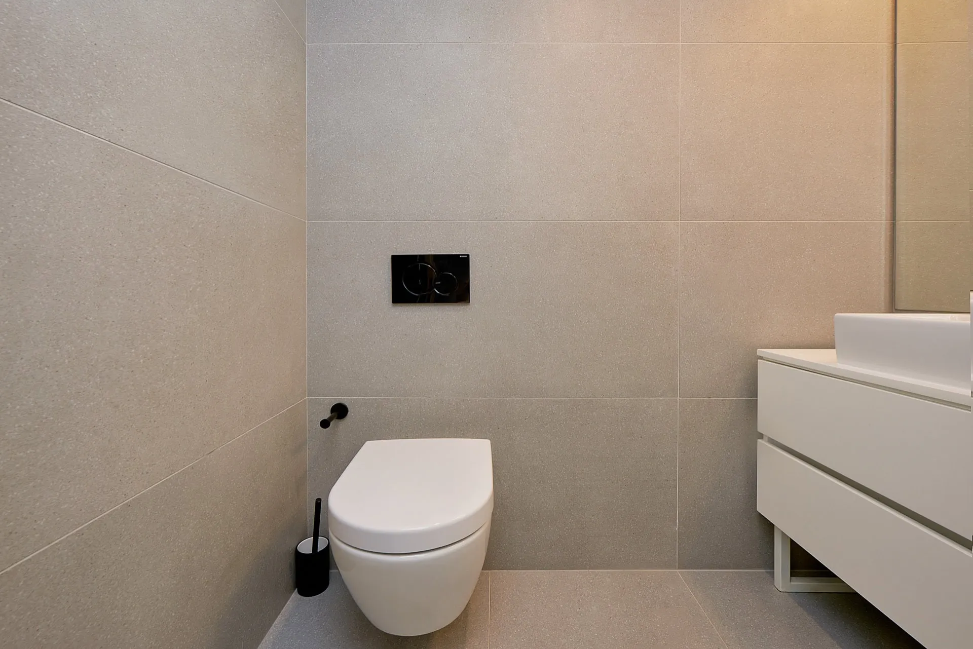 Savremeno kupatilo u stanu u Budvi, Crna Gora: viseća WC šolja, bela komoda i porcelanski pločice.
