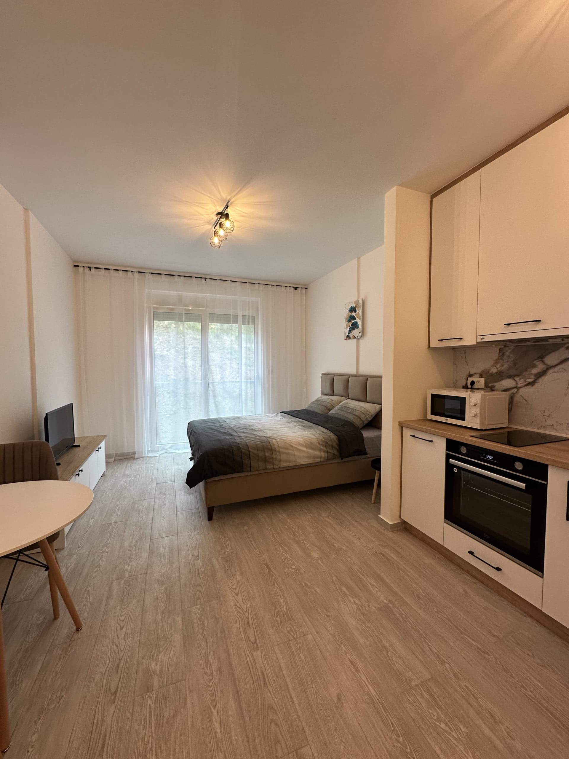 Moderne Studio in Bečići, Montenegro: Doppelbett, Einbauküche mit Geräten und Essbereich.