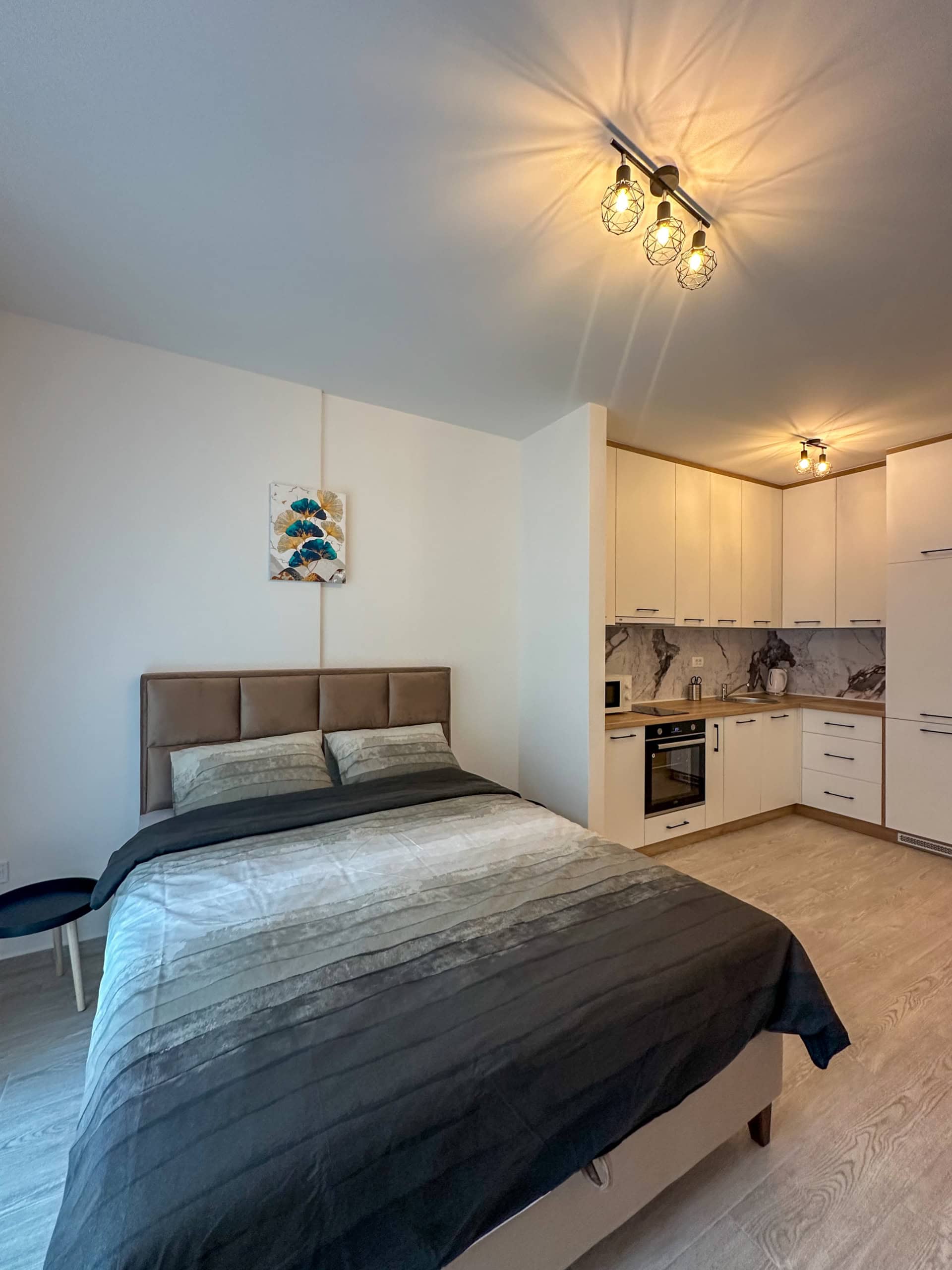 Moderne Studio mit Doppelbett und weißer Küche in einer Wohnung in Bečići, Montenegro.