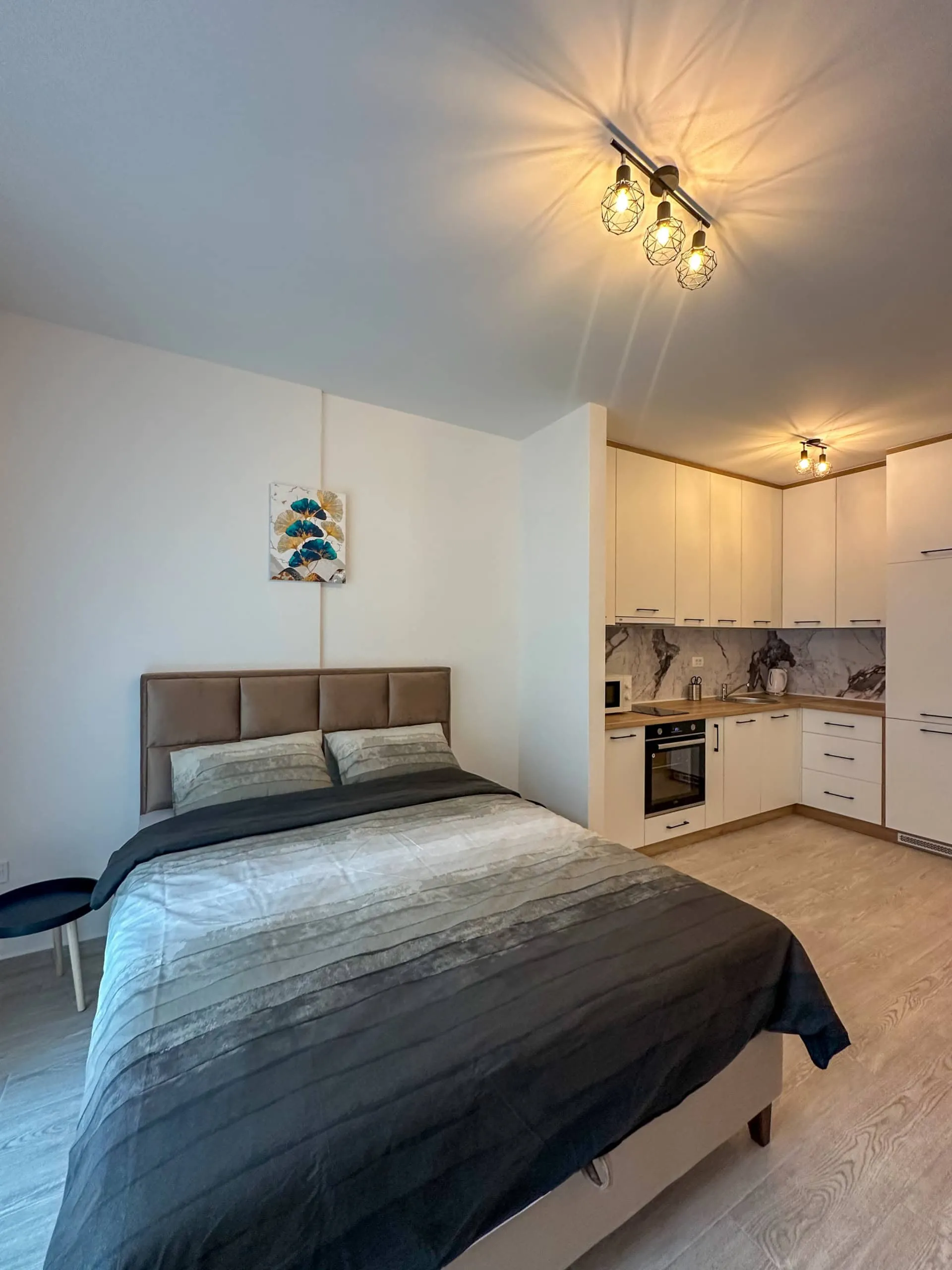 Moderne Studio mit Doppelbett und weißer Küche in einer Wohnung in Bečići, Montenegro.