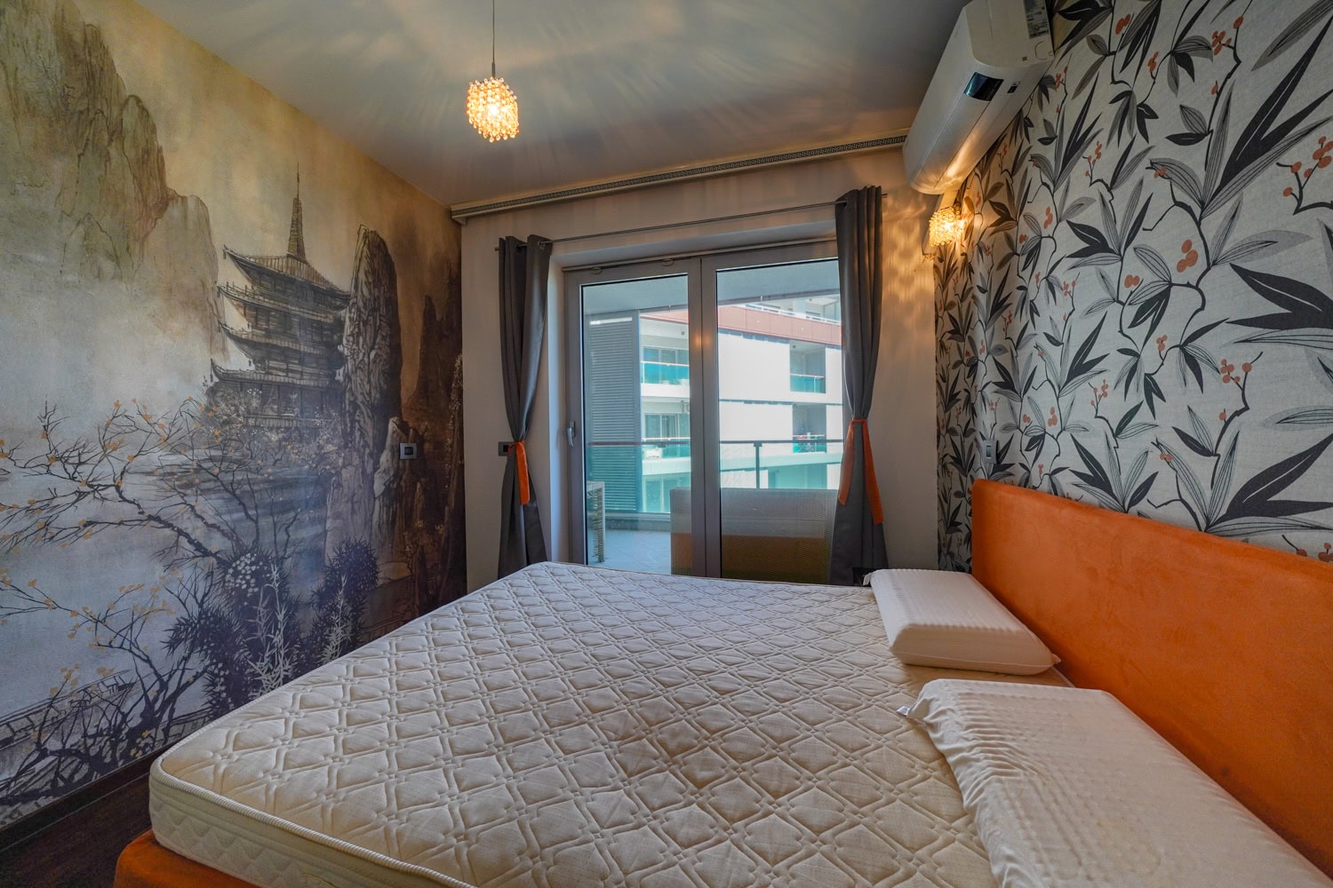 Schlafzimmer in einer Wohnung in Budva, Montenegro: Doppelbett, Designer-Tapete mit Landschaftsmotiv und Zugang zum Balkon.