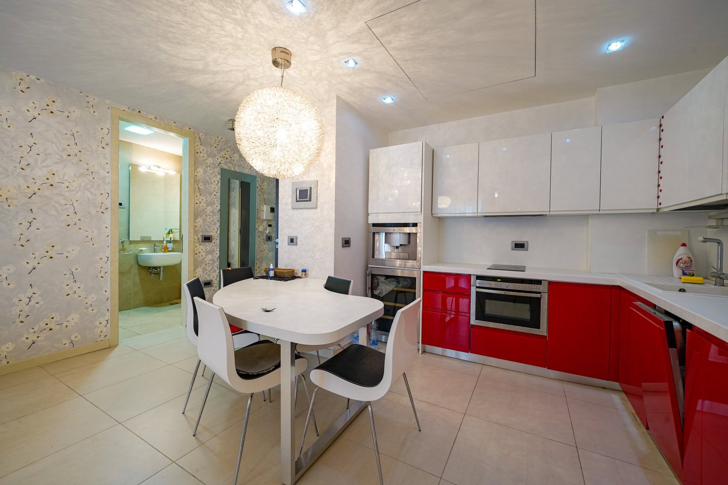 Moderne Wohnküche mit roter Einbauküche in einer Wohnung, Budva, Montenegro: Essbereich und Einbaugeräte.