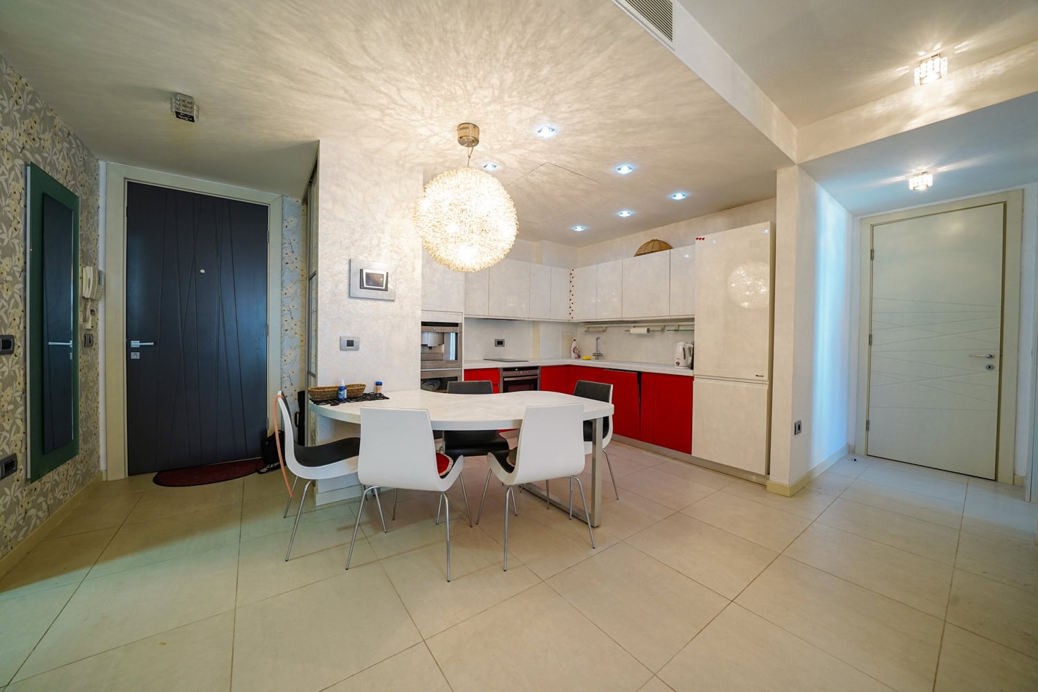 Moderne Wohnküche mit weißer Einbauküche in einer Wohnung in Budva, Montenegro: Essbereich und Einbaugeräte.