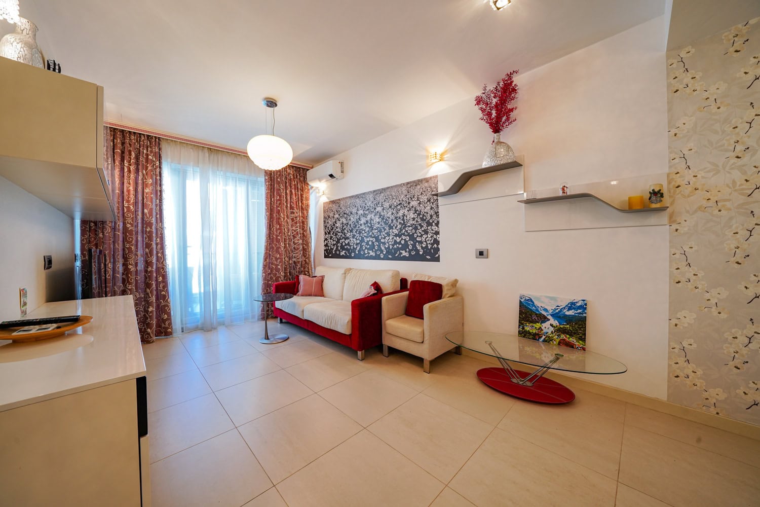 Gemütliches Wohnzimmer mit Polstermöbeln und Zugang zum Balkon in einer Wohnung in Budva, Montenegro. Modernes Interieur mit Dekor.