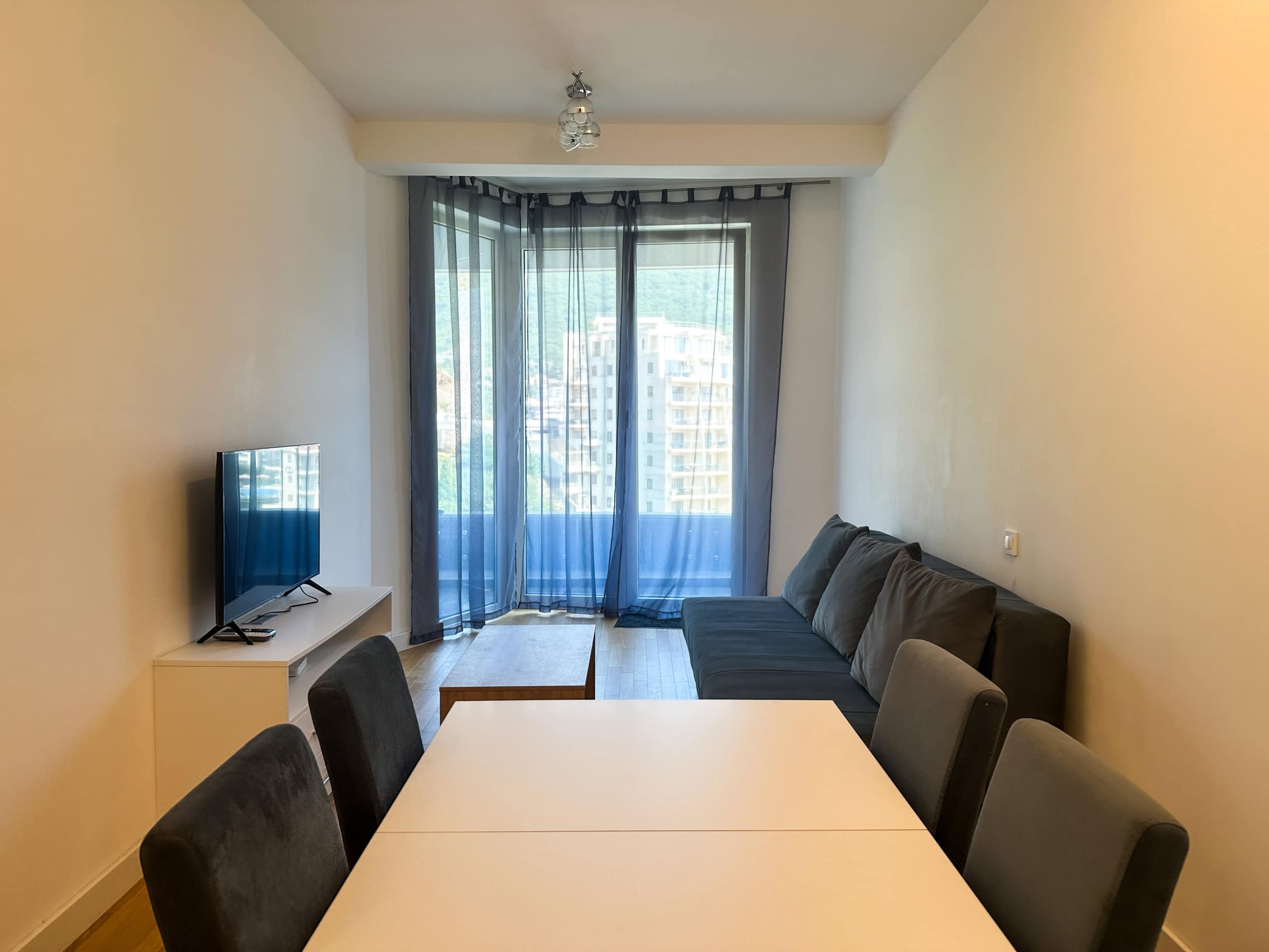 Salon z meblami, stołem jadalnym i panoramicznym oknem w mieszkaniu w Beczyczach, Czarnogóra